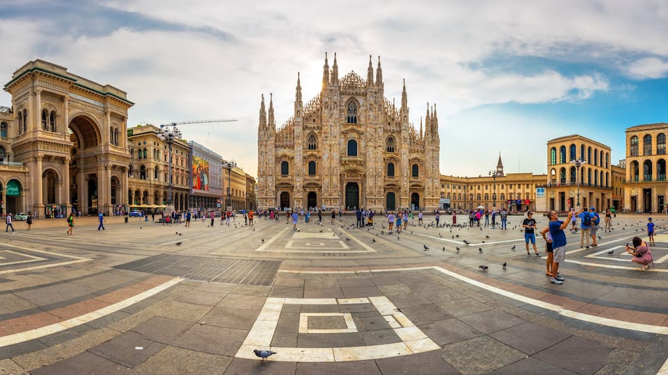 A large open square with a historic cathedral in the center, surrounded by classical architecture.