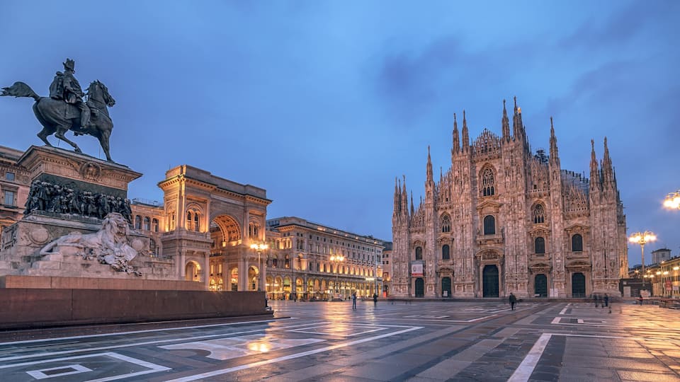 A grand cathedral with intricate Gothic architecture, a statue of a historical figure on horseback, and a spacious square with a fountain.