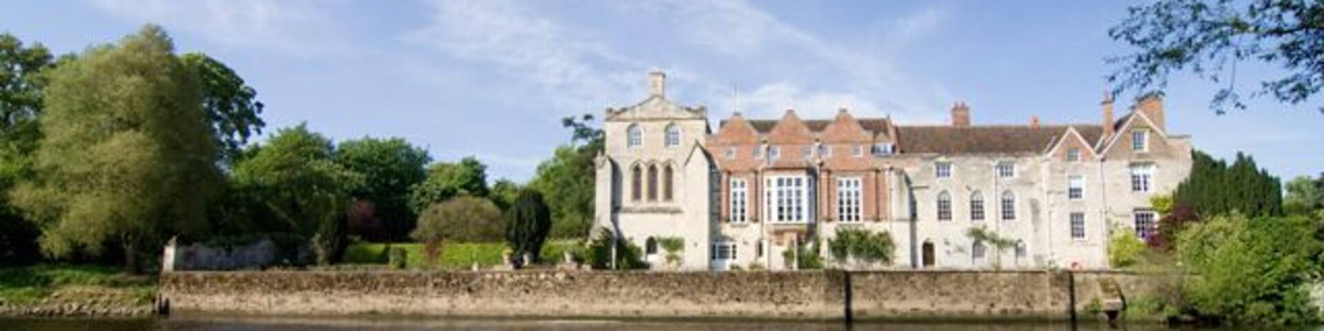 A large, historic building by a calm river.
