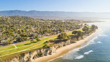 A coastal town with a beach, houses, and mountains in the background.