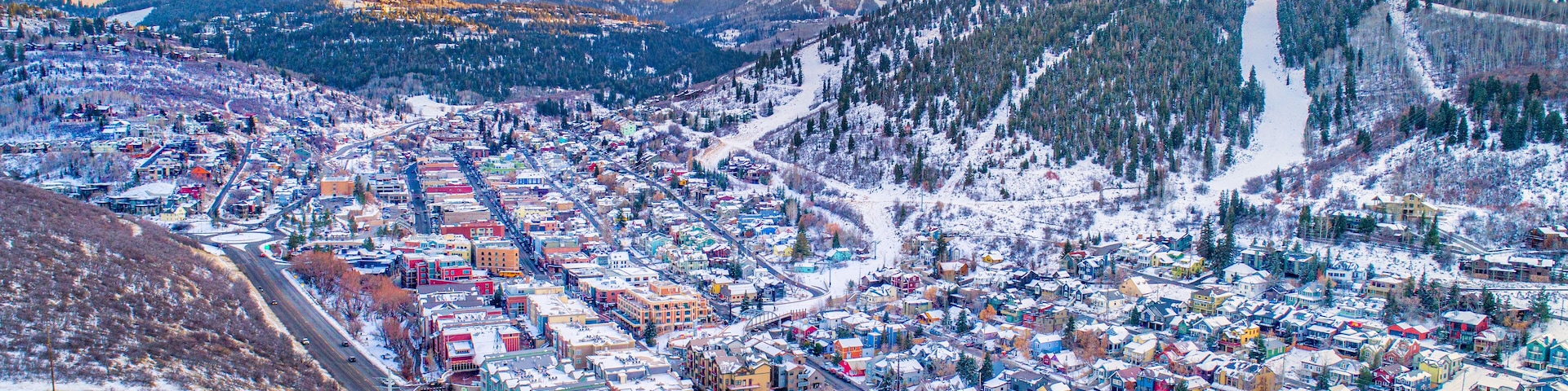 A snow-covered town with colorful buildings, surrounded by mountains and a ski slope.