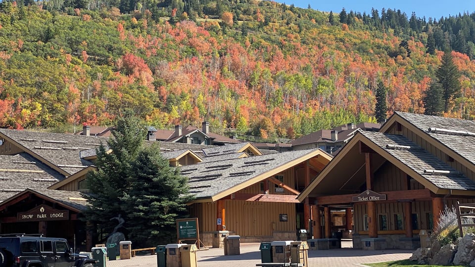 A lodge with a wooden facade, a ticket office, and a parking area with a Jeep in front.