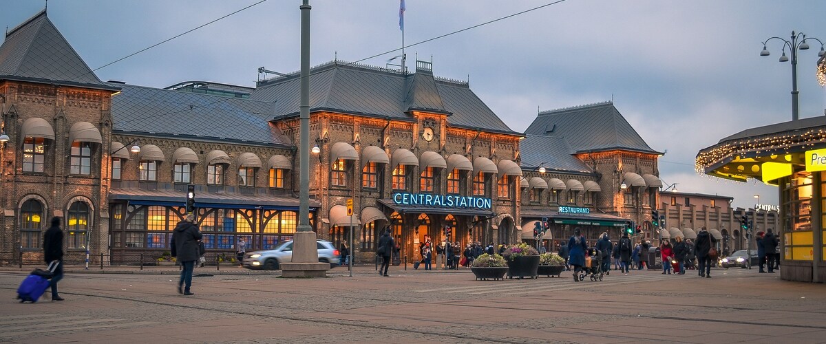 A historic train station with a clock tower, a restaurant, and a tram stop.