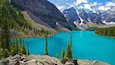 A turquoise lake surrounded by mountains and dense forests.