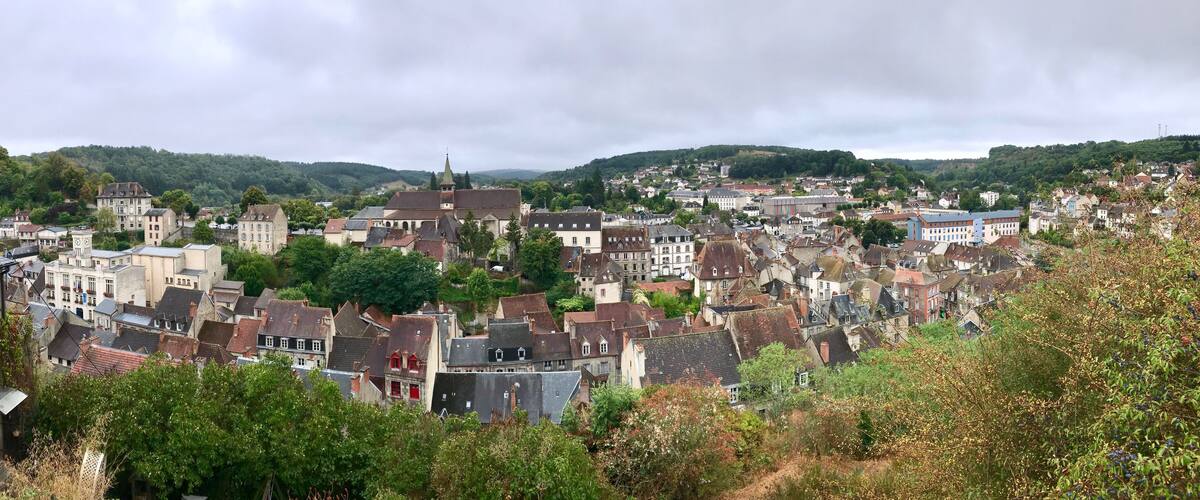 A historic town with a prominent church tower, surrounded by lush greenery and rolling hills.