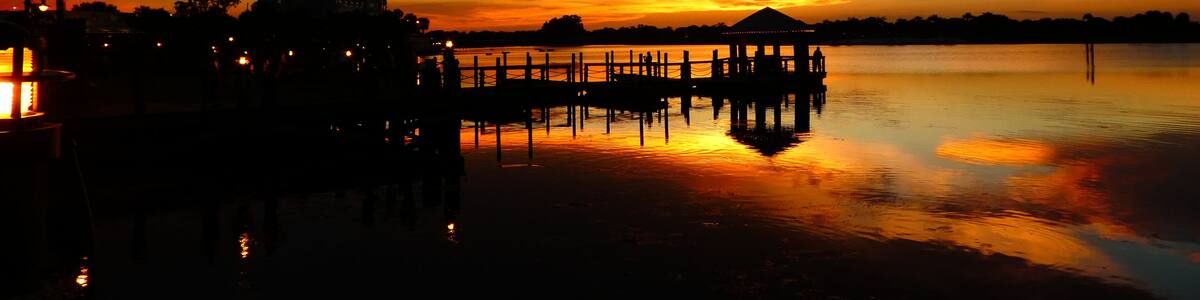 Un coucher de soleil sur un lac paisible, avec une jetée qui s’avance dans l’eau.