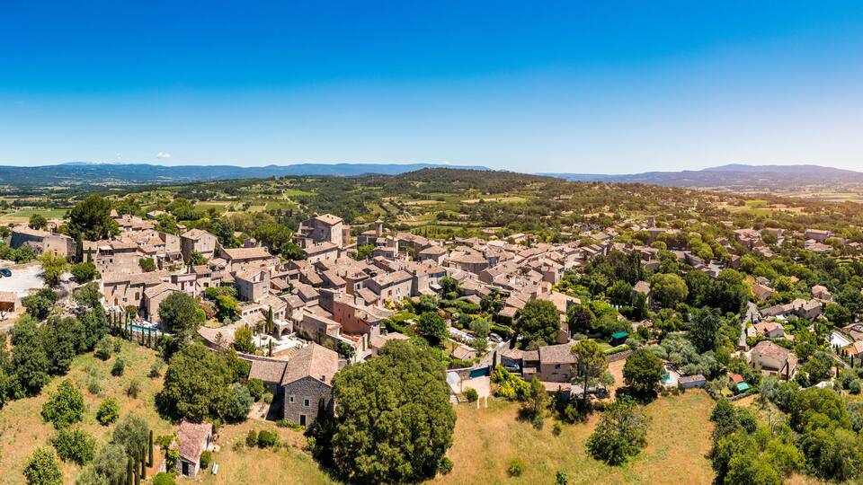 A historic town with medieval architecture, surrounded by lush greenery and rolling hills.