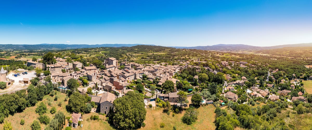 A historic town with medieval architecture, surrounded by lush greenery and rolling hills.