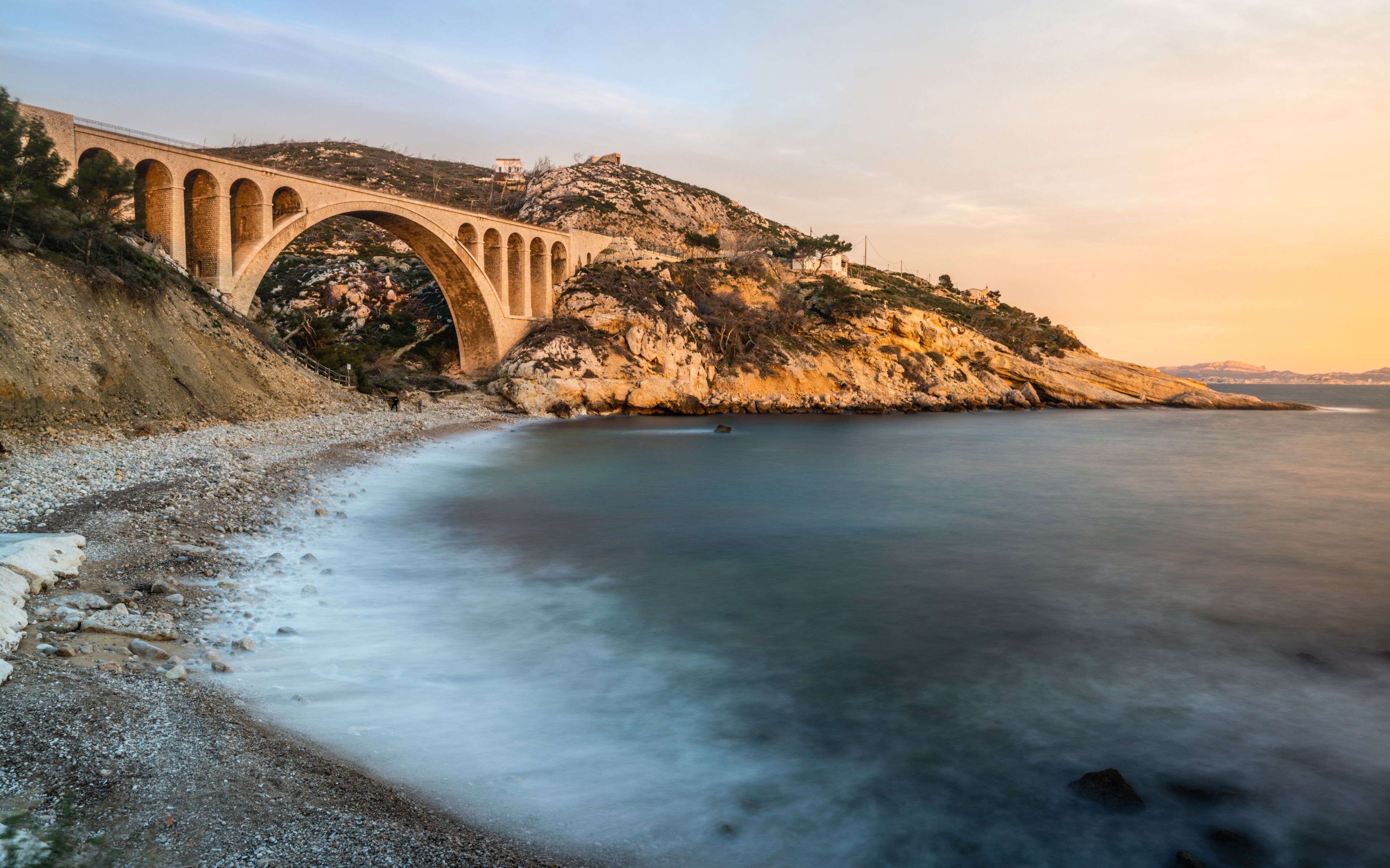 Sunset at Calanque des Eaux Salees or Salt water rocky inlet with Pebble beach and old railway bridge near Marseille France