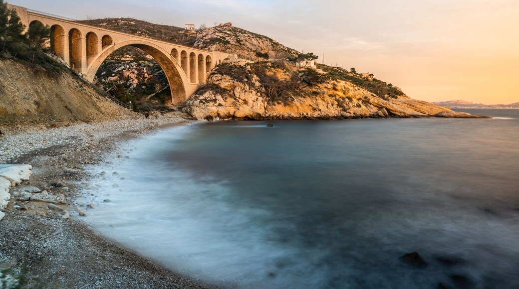 Sunset at Calanque des Eaux Salees or Salt water rocky inlet with Pebble beach and old railway bridge near Marseille France