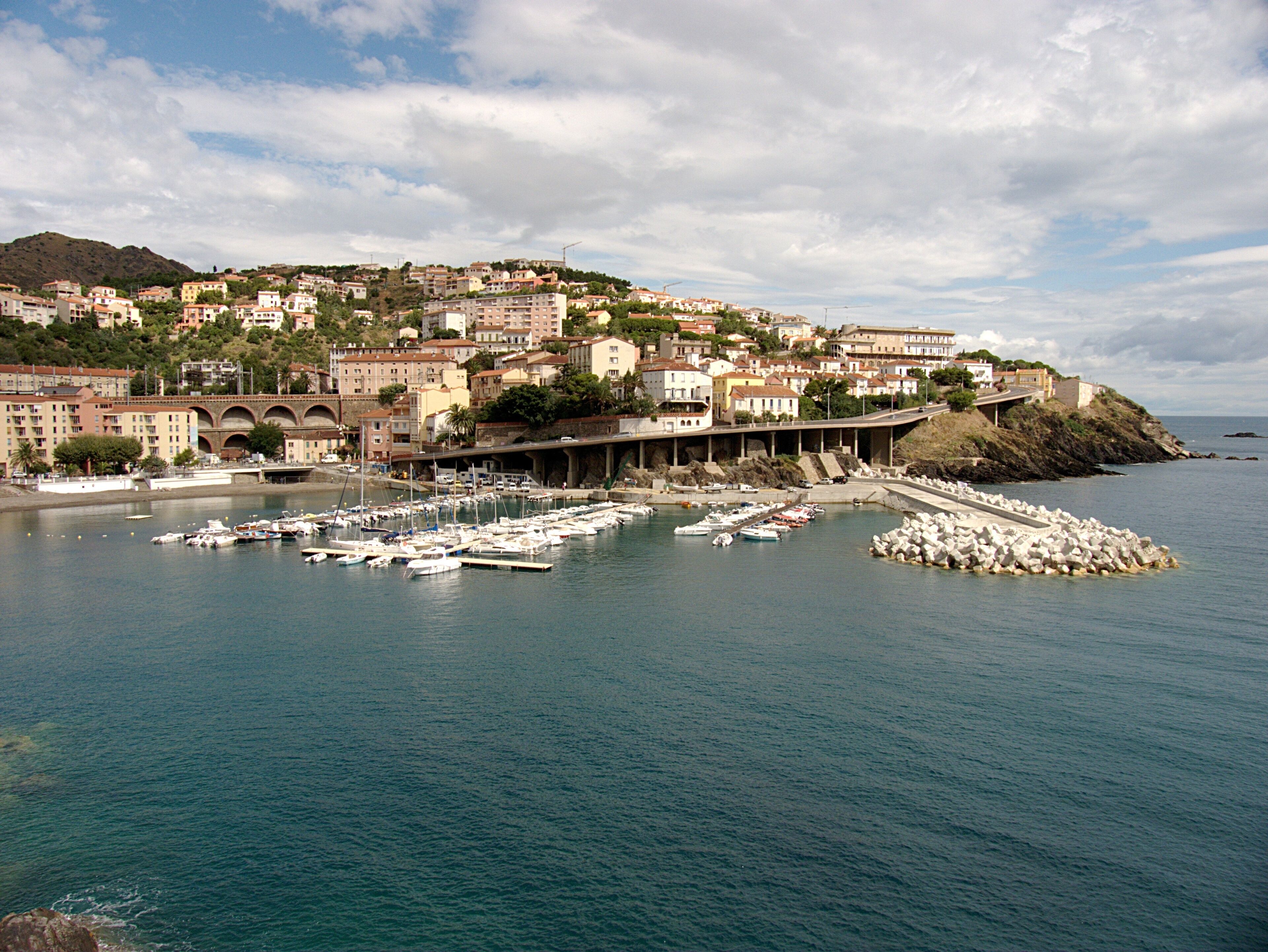 A coastal town with a marina, buildings, and a bridge.