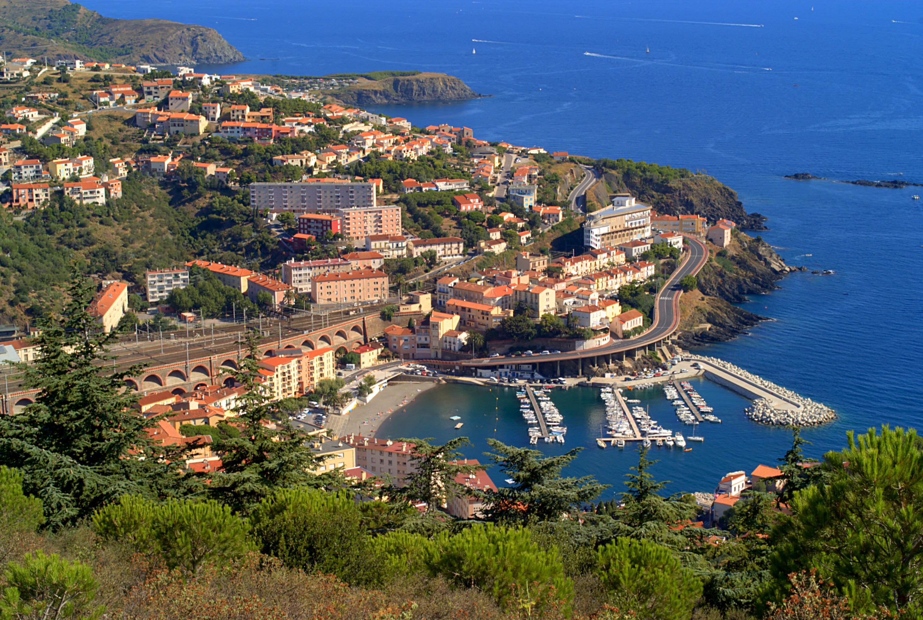 A coastal town with a marina, buildings, and a bridge.