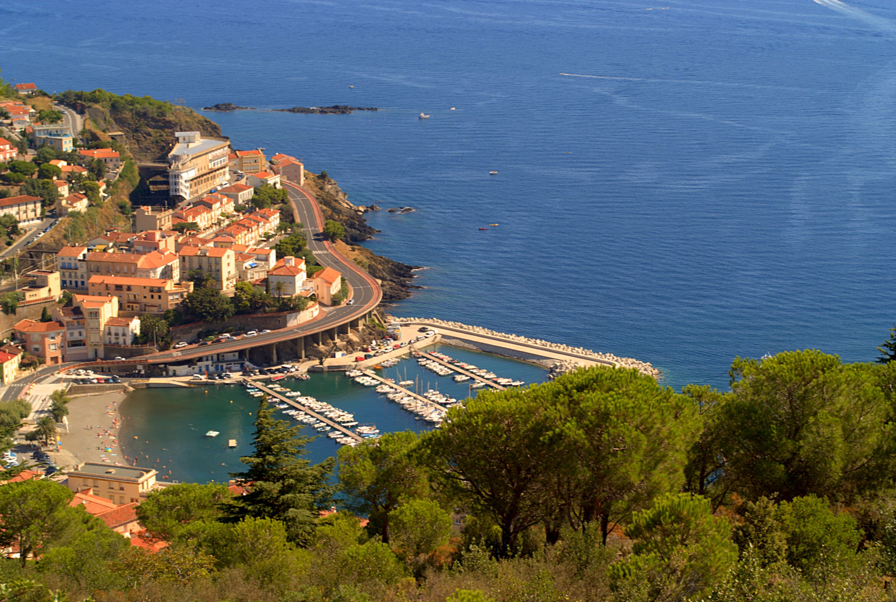 A coastal town with a marina, buildings, and a beach.