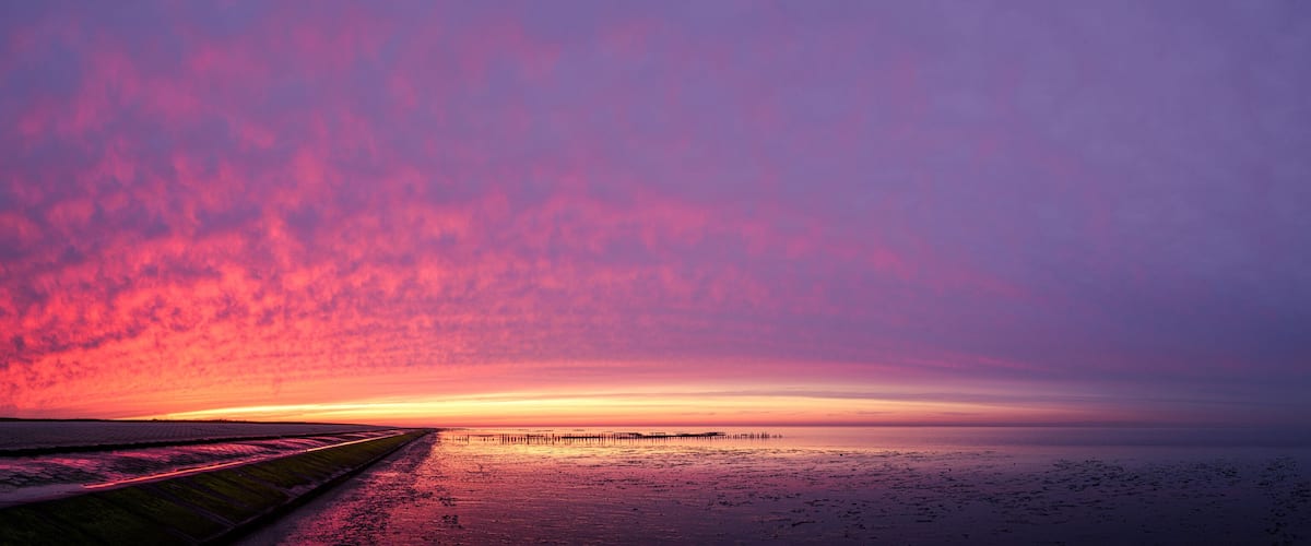 A sunset over a coastal area with a pier extending into the water.