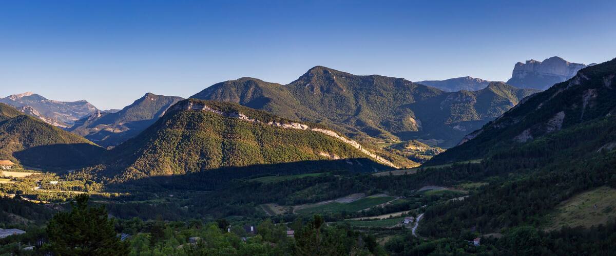 A mountainous landscape with a valley, a river, and scattered houses.