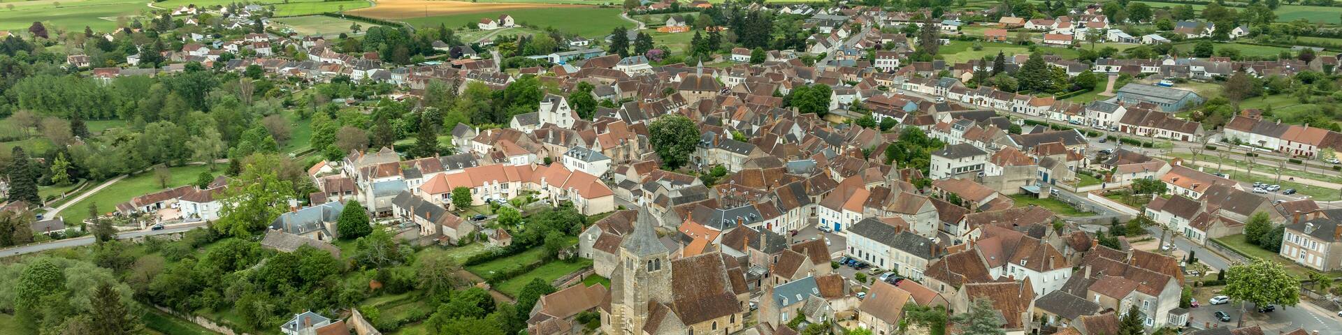 Aerial view of Ainay le Chateau, small medieval town in Allier department in France with ramparts and round towers surrounding the Saint Etienne gothic church