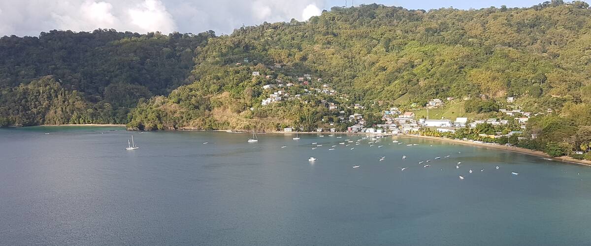 A coastal landscape with a bay, boats, and a hillside settlement.