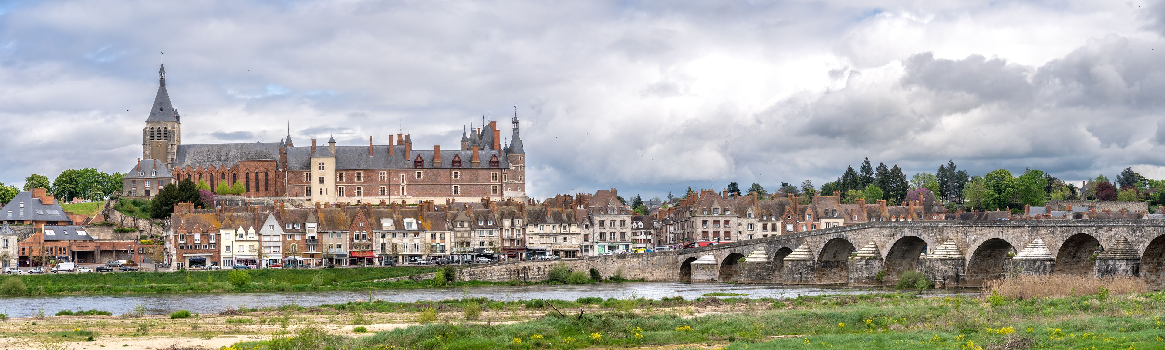 A historic town with a prominent church, a stone bridge, and a river.