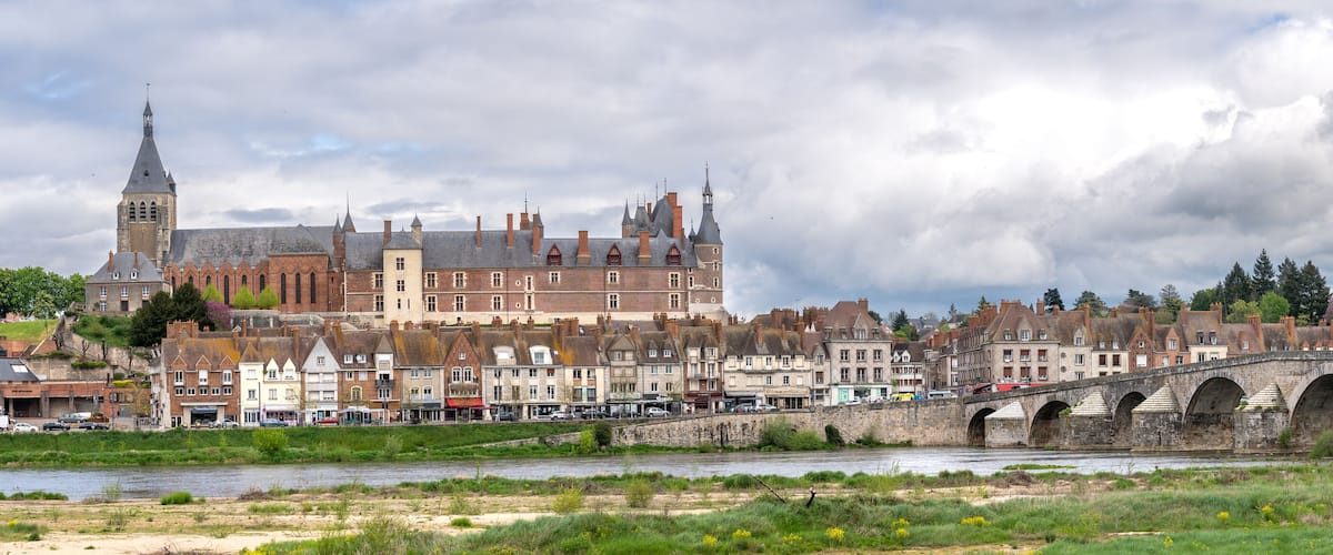 A historic town with a prominent church, a stone bridge, and a river.