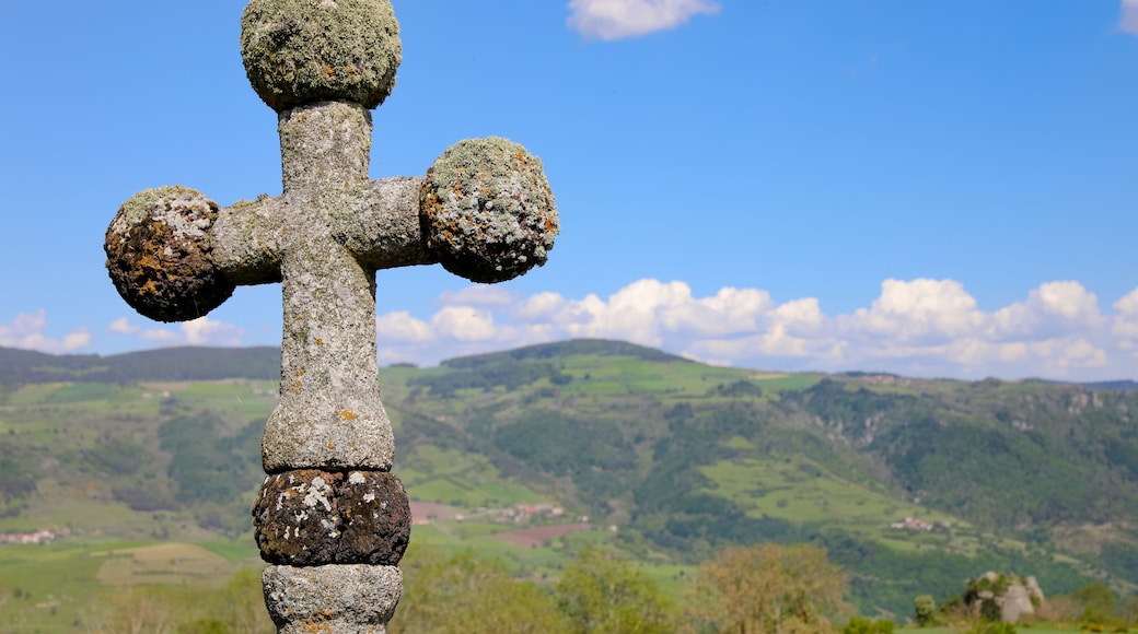 Croix de pierre au dessus d'une vallée en Haute Loire. Paysage de campagne vallonnée l'été en Auvergne. Nature, collines, forêts, champs et prairies à Charraix en France.