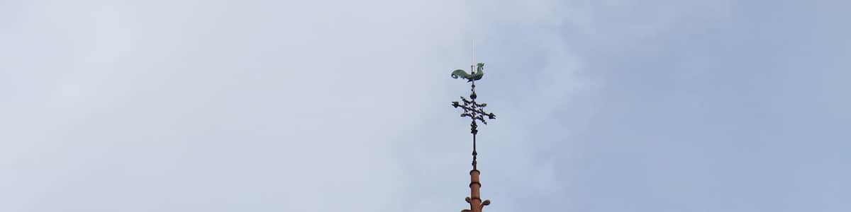 Un clocher d’église surmonté d’une horloge et d’une girouette.