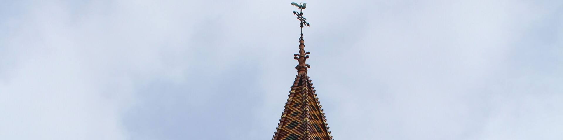 A tall brick tower with a clock and a pointed roof.