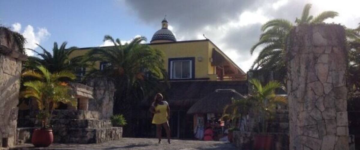 A building with a dome, palm trees, and stone steps leading up to it.