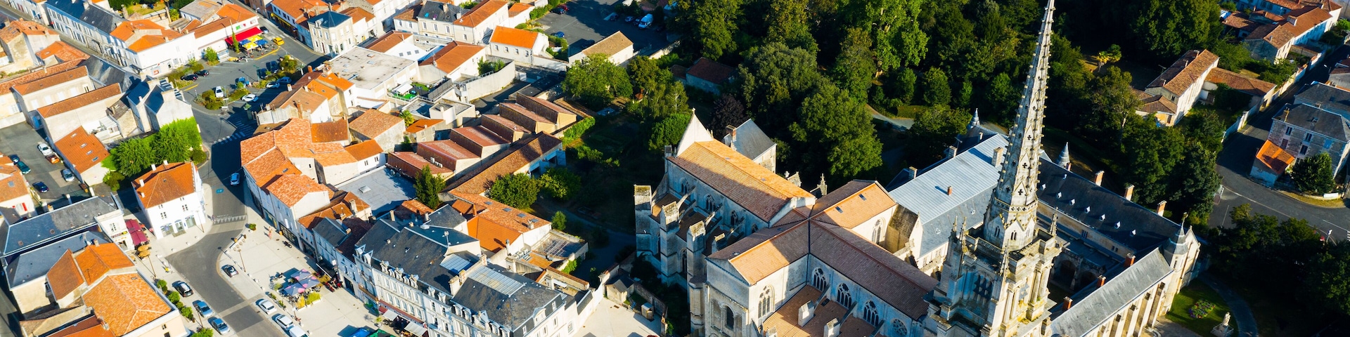 Vista aérea de uma cidade histórica com uma igreja imponente, ruas estreitas e edifícios residenciais.