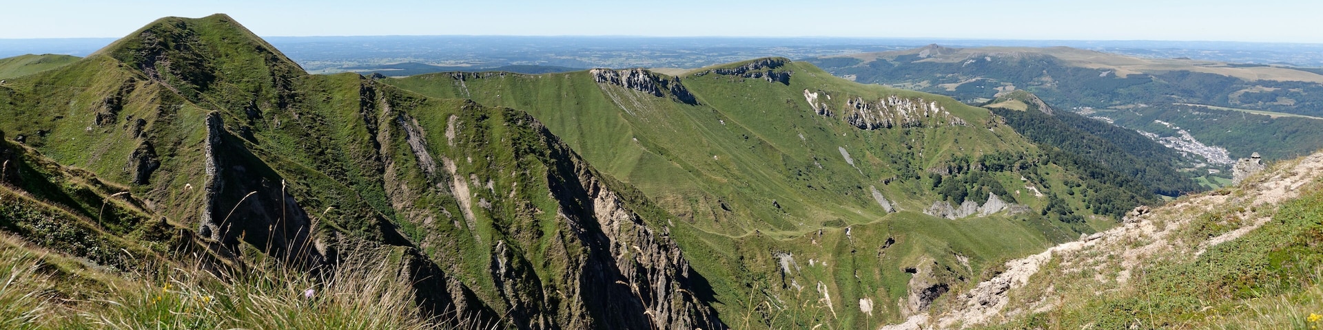Paisaje montañoso con laderas verdes y afloramientos rocosos.