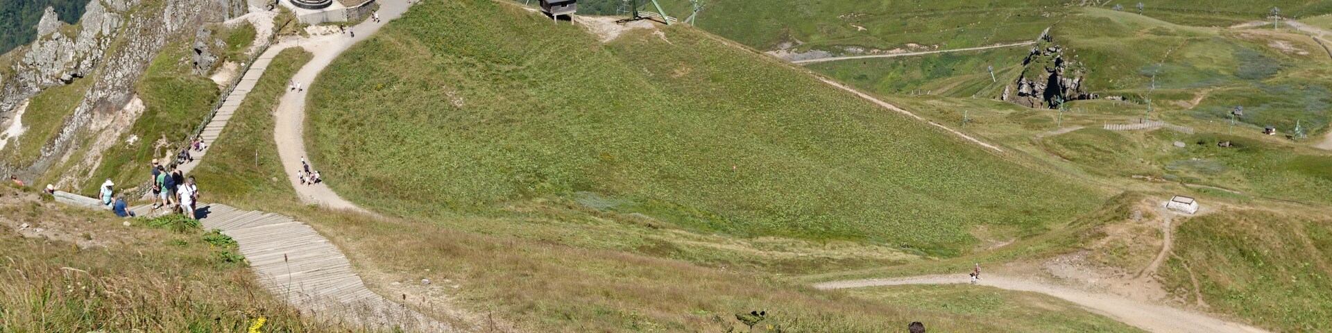 Un albergue de montaña con un camino sinuoso y una vista panorámica de colinas ondulantes.