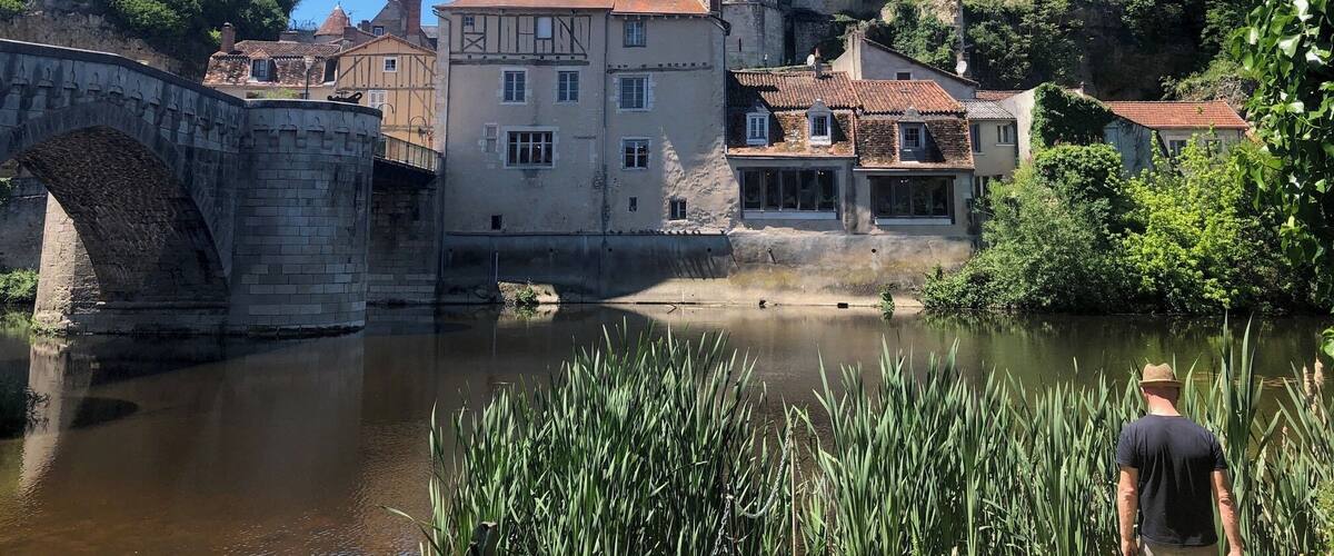 A historic town with a prominent church tower, a stone bridge, and a river.