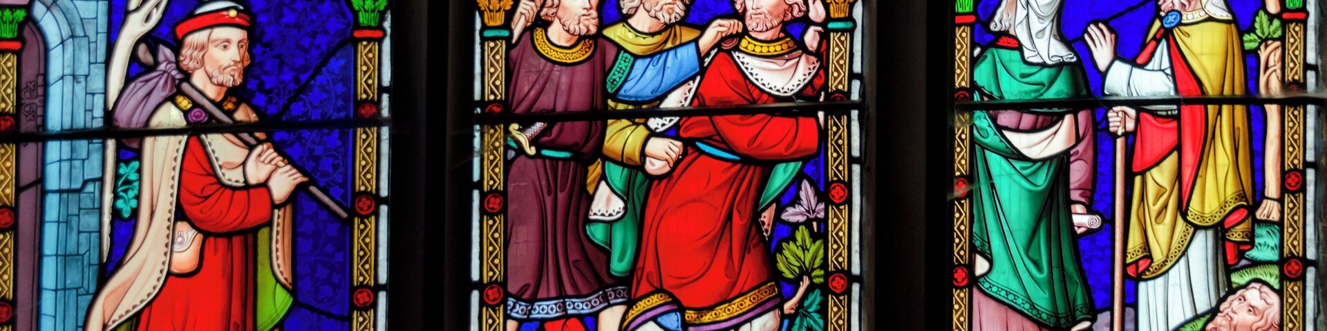 Una vidriera con figuras y símbolos religiosos.