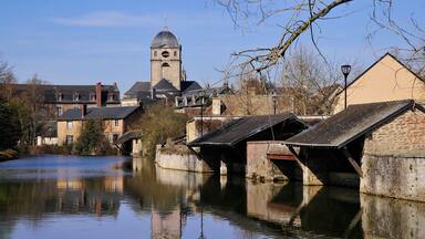 A calm river with a bridge and a tower in the background.