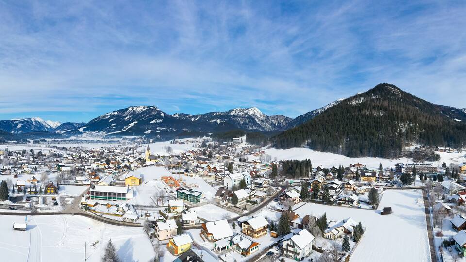 A snow-covered town with a prominent church, surrounded by mountains and a clear sky.