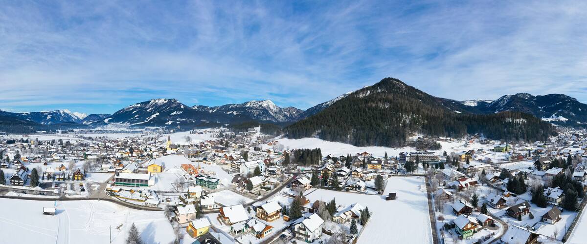 A snow-covered town with a prominent church, surrounded by mountains and a clear sky.