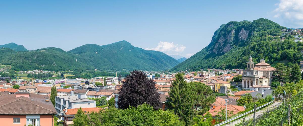A town with a prominent church and mountains in the background.
