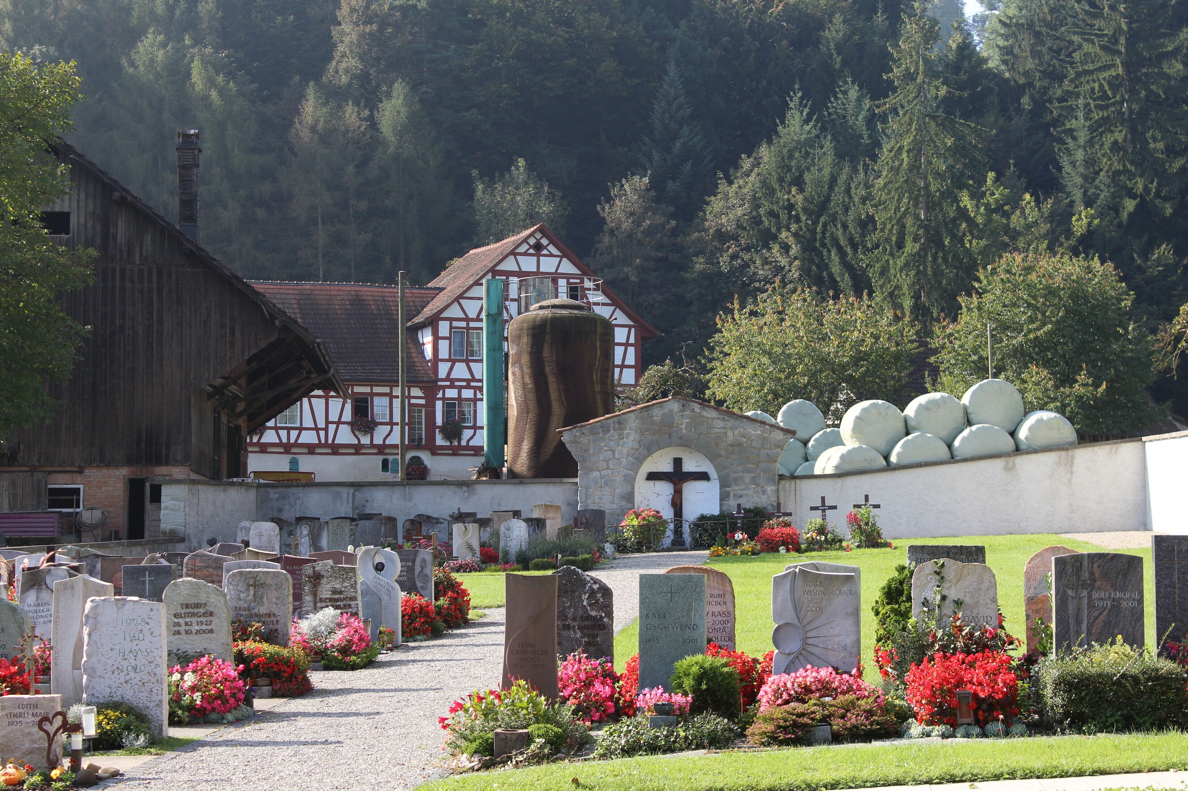 A cemetery with gravestones, a church, and a mountain backdrop.
