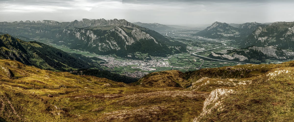 A mountainous landscape with a valley and a winding river.