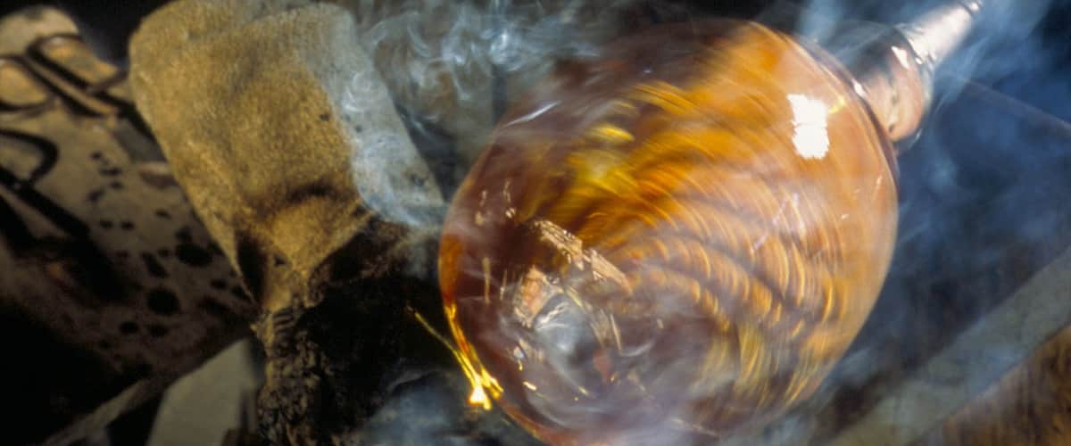 Un objet de verre à surface réfléchissante, peut-être une sculpture ou un objet décoratif, entouré de fumée ou de vapeur.