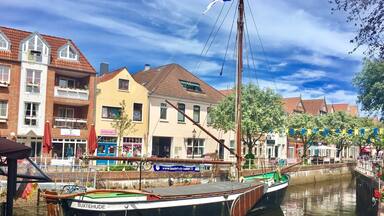 A canal with boats, a traditional building, and a flag.