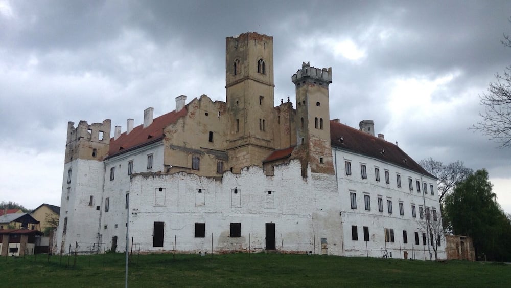 A historic castle with white walls and red-tiled roofs, featuring multiple towers and arched windows.