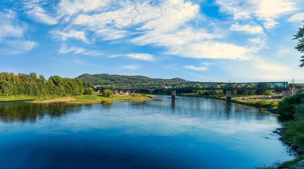 Panoramic view of the historic residence and railway bridge over the Elbe River under a blue summer sky in northern Bohemia, Czechia