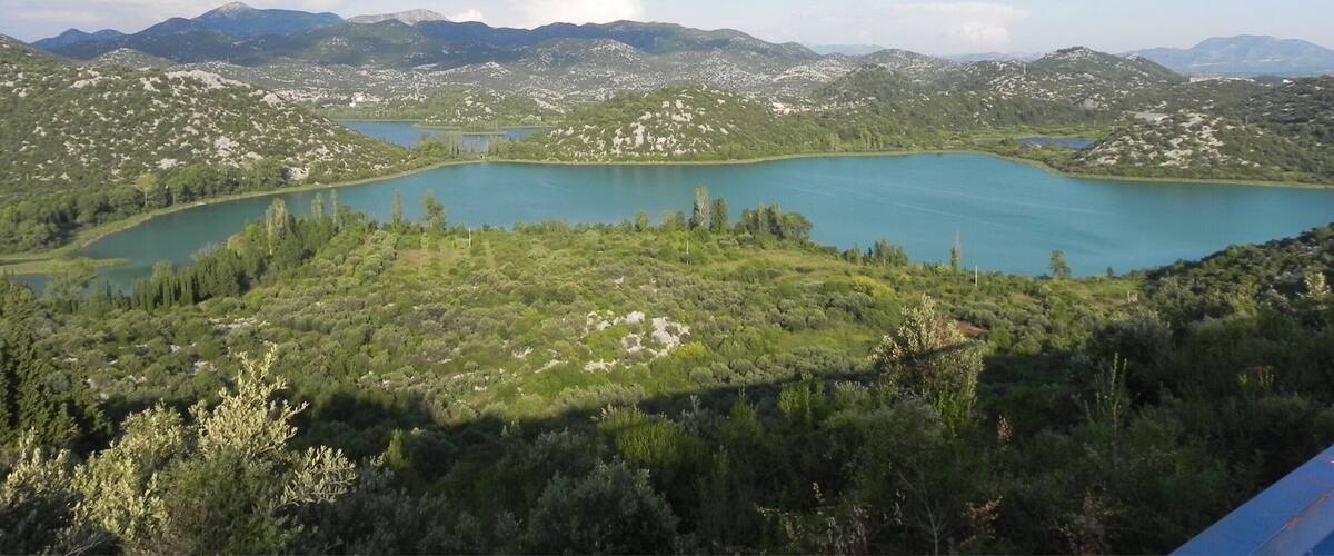 A lake surrounded by mountains and dense greenery.