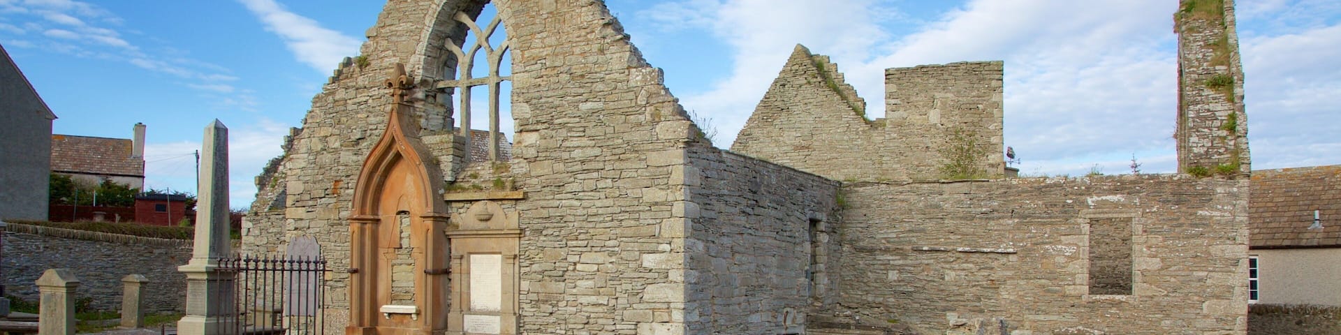 An old stone church with a pointed arch doorway and a tall bell tower.