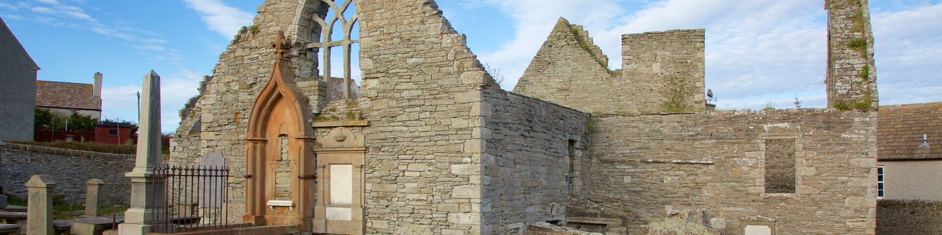 Una antigua iglesia de piedra con un arco apuntado y una alta torre campanario.
