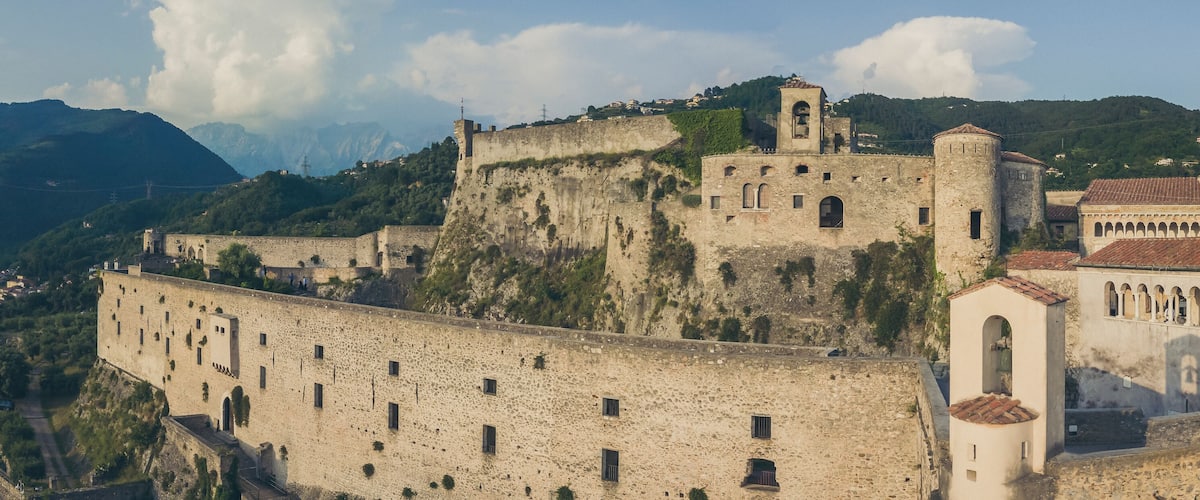 A historic fortified town with stone walls, towers, and a prominent church.