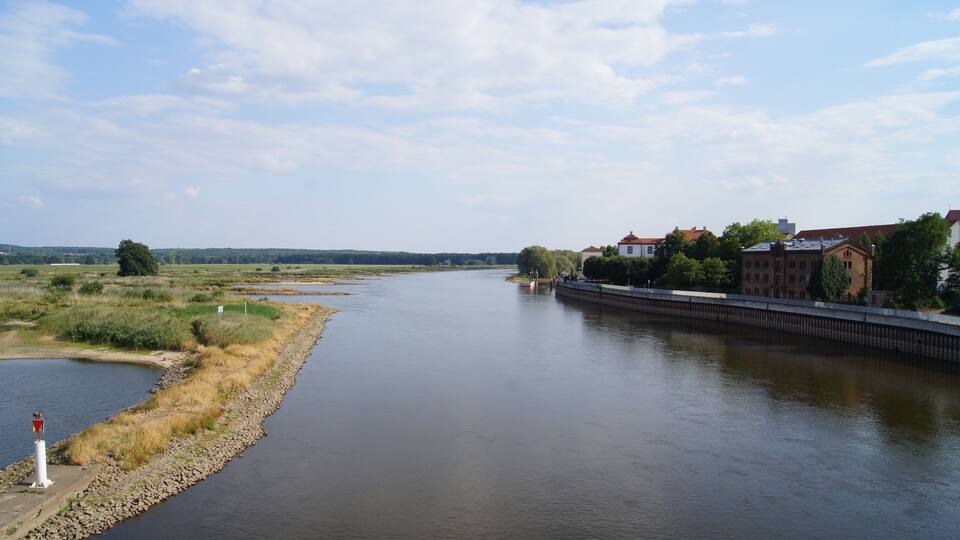 A river with a bridge, buildings, and a lighthouse.