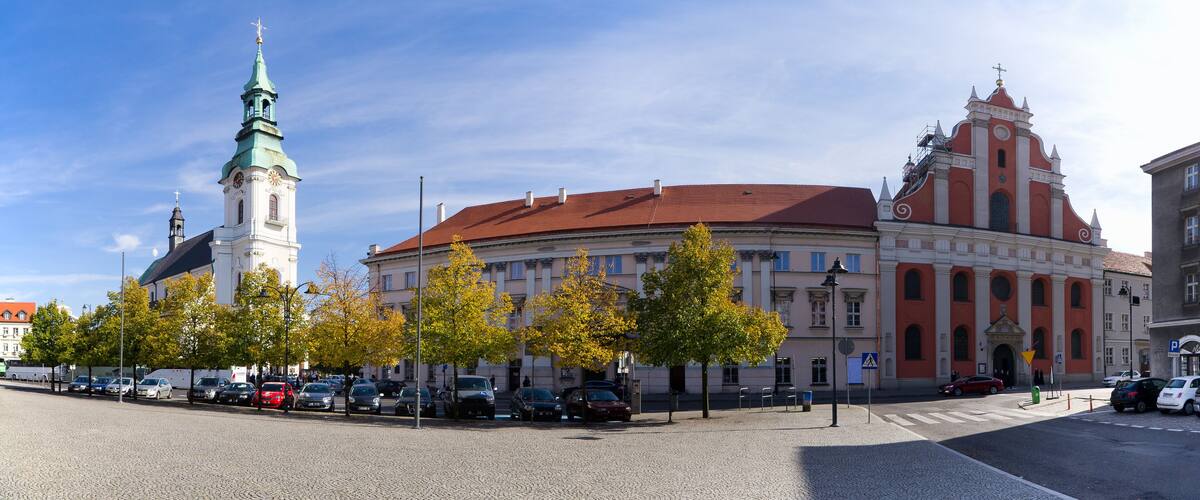 A historic building with a clock tower and a red-roofed structure.