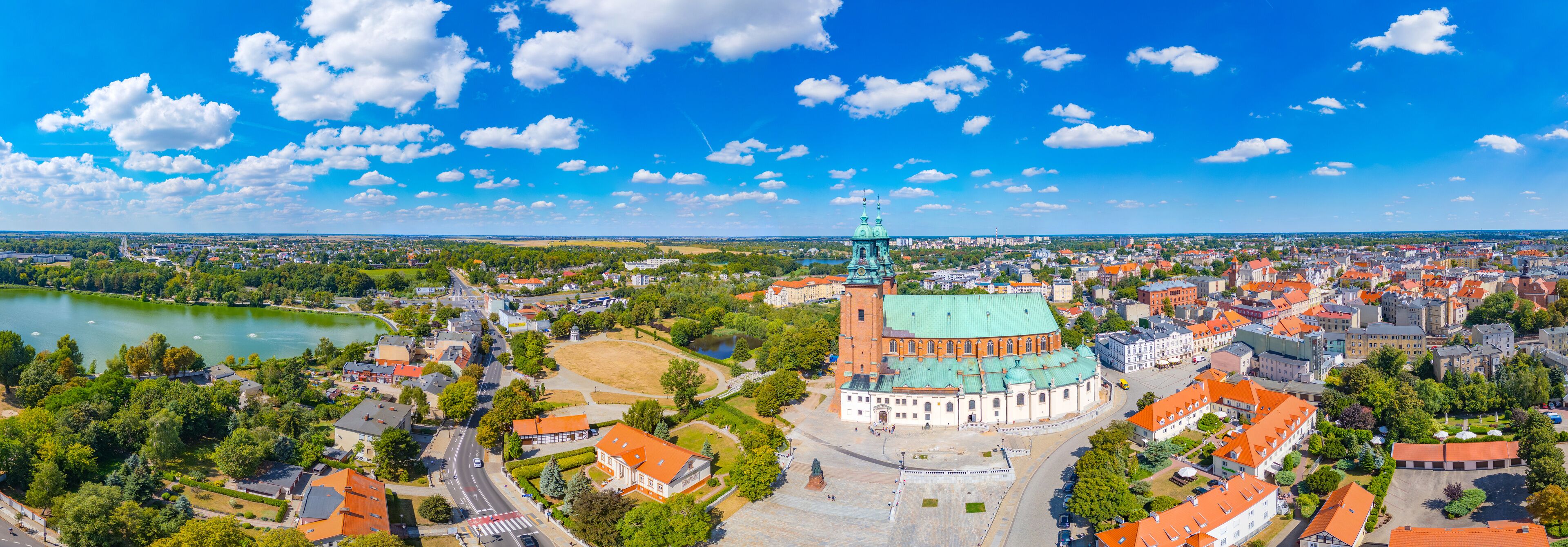 An aerial view of a city with a prominent church, a river, and surrounding greenery.