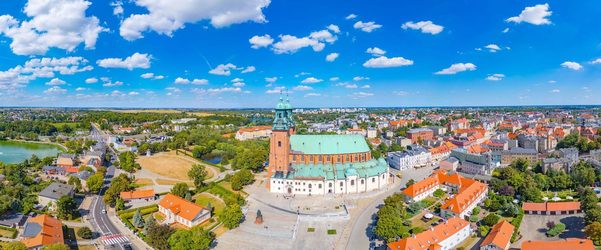 An aerial view of a city with a prominent church, a river, and surrounding greenery.